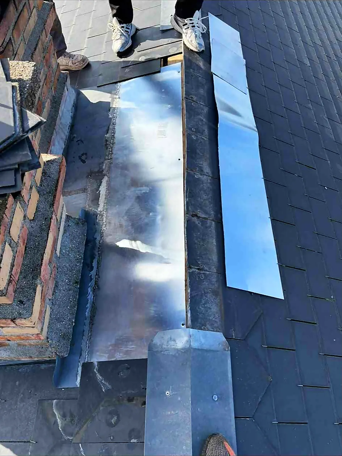 Bande de zinc neuve posée au pied d'une cheminée, chantier encore ouvert