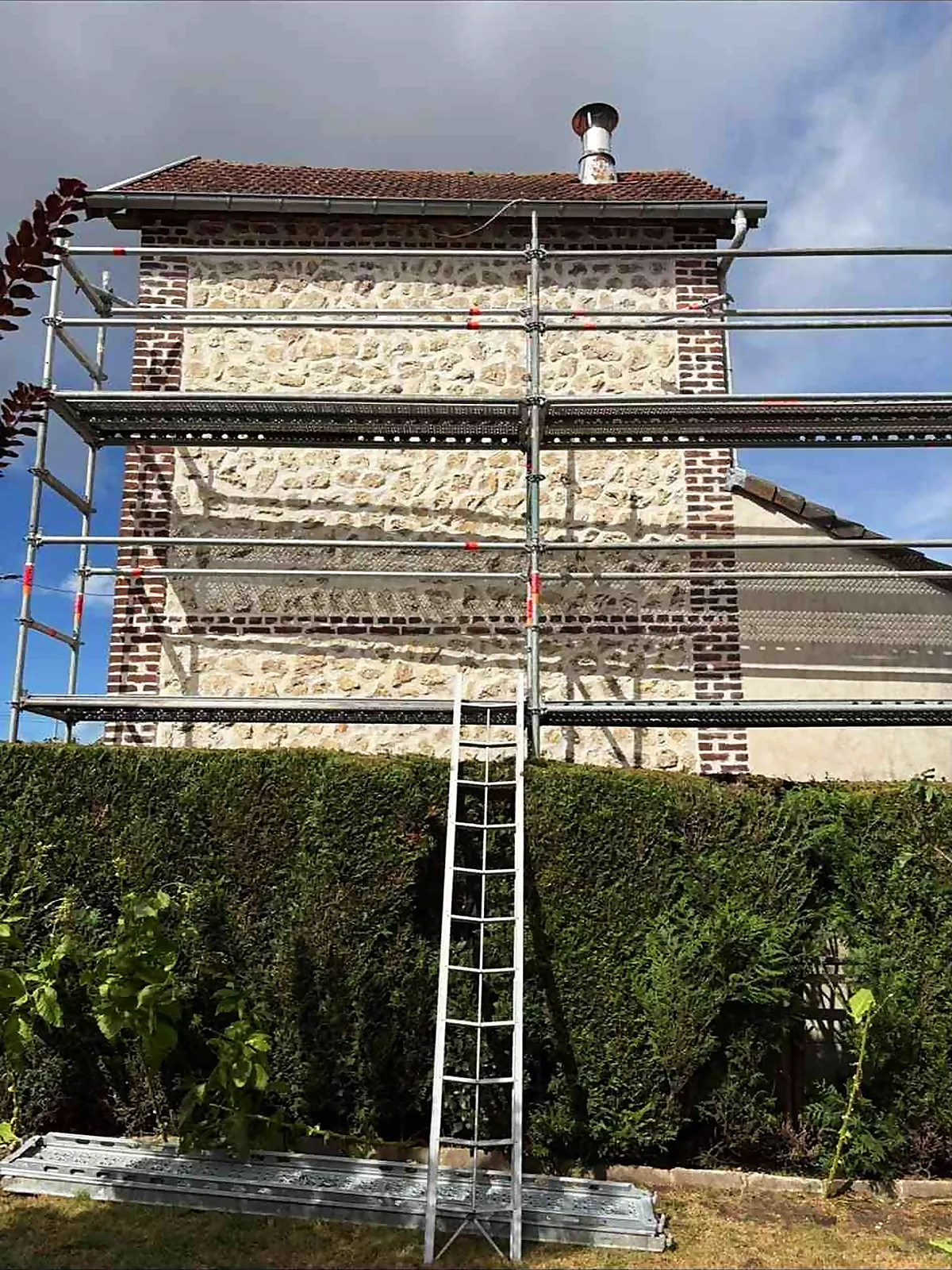 Échafaudage installé devant un pignon en pierre pour un rejointoiement
