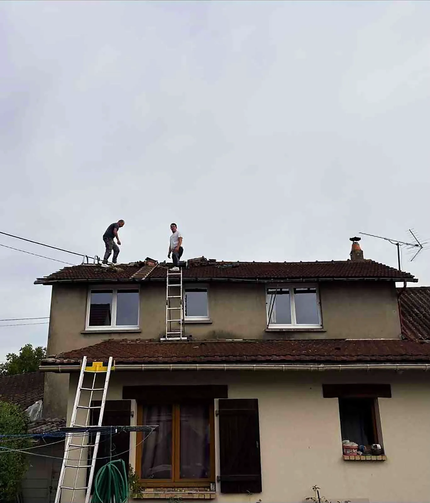 Deux couvreurs de l'entreprise travaillant sur une toiture en tuiles